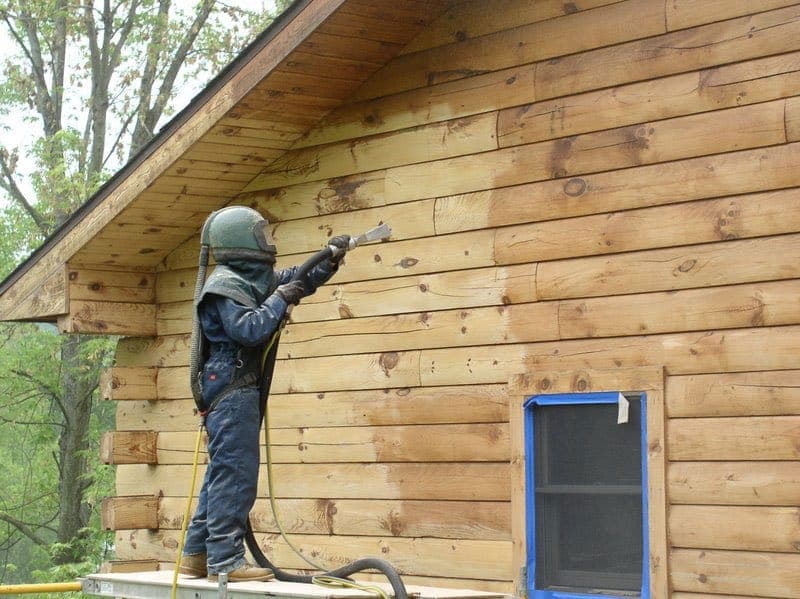 Aérogommage d'un mur en bois en combinaison de protection